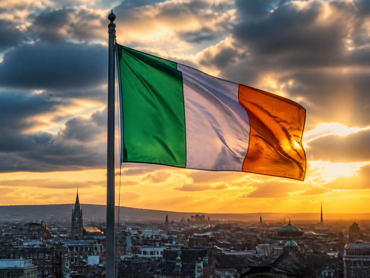 The Irish tricolour of green, white and orange flying over Dublin rooftops at sunset